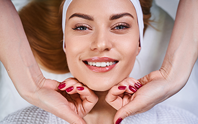 Smiling young girl is having good time while being treated by specialist hands in salon